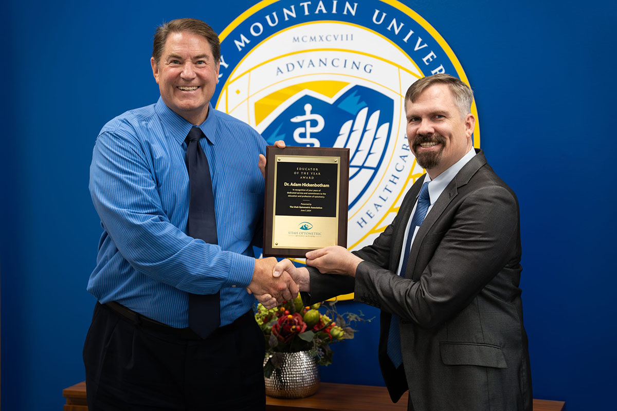 two men shaking hands holding optometry award