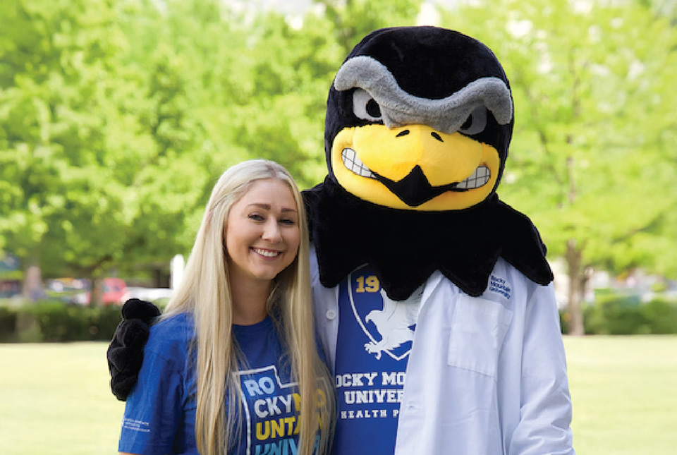 A student standing next to the school mascot.