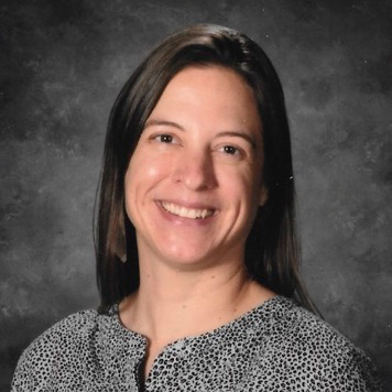 Woman in patterned blouse, neutral background.